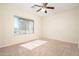 Cozy bedroom with neutral carpet, a ceiling fan, and a large window providing natural light at 17768 W Maui Ln, Surprise, AZ 85388