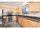 Close-up of the kitchen featuring stainless steel appliances, granite countertops, and natural wood cabinets at 17768 W Maui Ln, Surprise, AZ 85388