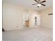 Spacious main bedroom with neutral carpet and a ceiling fan, leading to the bathroom and laundry room at 17768 W Maui Ln, Surprise, AZ 85388