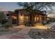 Charming stone home featuring a covered porch with wooden beams and professionally landscaped front yard at dusk at 17902 N 93Rd Way, Scottsdale, AZ 85255