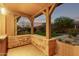 Covered patio with stone accents, offering an outdoor living space with views of a lush green yard and peaceful surroundings at 17902 N 93Rd Way, Scottsdale, AZ 85255