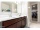 Bathroom featuring a double sink vanity, a large mirror, and a view into the walk-in closet at 18621 W Hackamore Dr, Surprise, AZ 85387