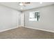 This bedroom features neutral walls, neutral carpet, a ceiling fan, and a window at 2032 W Eugie Ave, Phoenix, AZ 85029