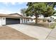 Single-story home featuring a brick exterior, a large driveway, and mature trees in a suburban setting at 2032 W Eugie Ave, Phoenix, AZ 85029