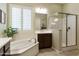 Bright bathroom with a soaking tub, walk-in shower, dark wood cabinets, and plantation shutters at 20594 S 194Th Pl, Queen Creek, AZ 85142