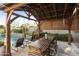 A wood pergola covers an outdoor dining area with seating next to the refreshing pool at 20594 S 194Th Pl, Queen Creek, AZ 85142