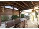 Outdoor dining area with wood pergola, outdoor grill, manicured bushes and stone pavers at 20594 S 194Th Pl, Queen Creek, AZ 85142