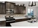 Close-up of the kitchen with stainless steel appliances, dark wood cabinets, and a stylish backsplash at 20780 N Gardenia Rd, Maricopa, AZ 85138