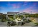 Cozy backyard with a stone fire pit surrounded by chairs, perfect for outdoor relaxation at 26764 W Ponderosa Ln, Buckeye, AZ 85396