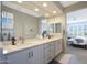 Well-lit bathroom with double sinks, white countertops, modern fixtures, and ensuite access to the main bedroom at 26764 W Ponderosa Ln, Buckeye, AZ 85396