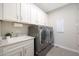 Well-equipped laundry room features modern washer and dryer, ample storage cabinets, and a convenient utility sink at 26764 W Ponderosa Ln, Buckeye, AZ 85396