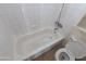 White tiled bathroom features a shower-tub combo and a matching toilet and a small cabinet at 3452 E Evans Dr, Phoenix, AZ 85032