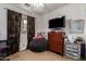 This bedroom has a large dark beanbag chair, dresser with TV, and decorative dark curtains at 3588 S 257Th Ave, Buckeye, AZ 85326