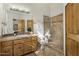 Bathroom with a walk-in shower, wood cabinets, and travertine countertops at 36102 N Creek View Ln, Cave Creek, AZ 85331