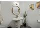 Stylish powder room features a pedestal sink, round mirror, unique artwork, and rustic-chic decor at 36102 N Creek View Ln, Cave Creek, AZ 85331