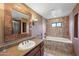 Bathroom featuring granite counters, a soaking tub, and decorative mirror at 36601 N Mule Train Rd # C38, Carefree, AZ 85377