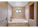 Tiled tub and shower combo with brushed gold fixtures and a window at 36601 N Mule Train Rd # C38, Carefree, AZ 85377