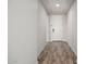 Hallway featuring wood-look tile floors and a white front door, leading into the home at 4187 N 183Rd Dr, Goodyear, AZ 85395