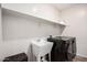 Practical laundry room featuring a utility sink, shelving, and modern washer and dryer at 4187 N 183Rd Dr, Goodyear, AZ 85395