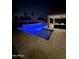 A serene and inviting backyard pool is illuminated at night with a covered patio and outdoor lounge area at 4187 N 183Rd Dr, Goodyear, AZ 85395