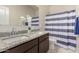 Bathroom with double sinks, granite counters, and a blue and white striped shower curtain at 5180 E Diatomite Dr, San Tan Valley, AZ 85143