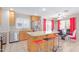 Bright kitchen with stainless steel appliances, island with seating, and adjacent dining area with vibrant red curtains at 6219 W Navajo Dr, Glendale, AZ 85302