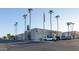 Exterior of a clubhouse in a beautiful location, showing palm trees, an American flag, and ample parking at 10106 W Highwood Ln, Sun City, AZ 85373