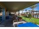 Inviting covered patio area with outdoor seating and ping pong table overlooking lush green space and pool at 10547 E Relativity Ave, Mesa, AZ 85212