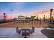 Scenic community playground with swing sets, slides, and picnic tables with a vibrant sunset sky at 10547 E Relativity Ave, Mesa, AZ 85212