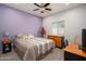 Bright bedroom with purple accent wall, featuring neutral carpeting, a ceiling fan and a study area at 10817 W Swayback Pass, Peoria, AZ 85383