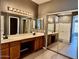 Bathroom with dual sinks, mirror, and walk-in shower behind glass doors at 11029 W Oraibi Dr, Peoria, AZ 85373