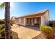 Rear exterior view of the home highlighting the screened porch, stone patio, and manicured landscaping at 11029 W Oraibi Dr, Peoria, AZ 85373