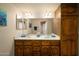 Well-lit bathroom with dual sinks, wood cabinets and a full mirror at 12222 N Paradise Village S Pkwy # 405, Phoenix, AZ 85032