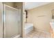 Bright bathroom features a stand-up shower, soaking tub, and neutral tile flooring at 13025 W Gelding Dr, El Mirage, AZ 85335