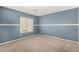 A bright bedroom has fresh blue paint, neutral carpet, and a window with horizontal blinds at 13025 W Gelding Dr, El Mirage, AZ 85335