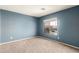 Well-lit bedroom with large window showcasing neighborhood views and neutral carpet at 13025 W Gelding Dr, El Mirage, AZ 85335