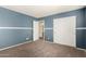 Bedroom featuring new neutral carpet, blue accent walls with white trim, and sliding closet doors at 13025 W Gelding Dr, El Mirage, AZ 85335