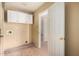 Laundry room featuring tile floors, white cabinets, and a door to another room at 13025 W Gelding Dr, El Mirage, AZ 85335