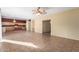 Open living area featuring tile floors, a ceiling fan, and an adjacent kitchen with an island and ample cabinets at 13025 W Gelding Dr, El Mirage, AZ 85335