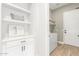 Hallway with cabinets and shelves, leading to laundry room with white washer and dryer at 13314 W Dale Ln, Peoria, AZ 85383