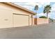 Beige single-car garage and peach courtyard wall, accented by palm trees and blue sky at 13354 W Stonebrook Dr, Sun City West, AZ 85375