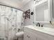 Well-lit bathroom featuring white cabinetry, a framed mirror, a floral shower curtain, and wall shelving at 1357 N Balboa Dr, Gilbert, AZ 85234