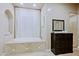 Bathroom with tub, tile surround, dark dresser and white curtains at 13935 E Smokehouse Trl, Scottsdale, AZ 85262