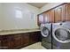 Modern laundry room features stainless steel washer and dryer, with granite counters and dark wood cabinets at 13935 E Smokehouse Trl, Scottsdale, AZ 85262