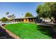 Large backyard featuring artificial grass, mature trees, and a covered patio for relaxation and recreation at 1755 W Lawrence Ln, Phoenix, AZ 85021