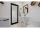 Modern bathroom featuring a unique pedestal sink, black framed door, mirror and white tile flooring at 1755 W Lawrence Ln, Phoenix, AZ 85021