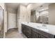 Bathroom vanity features dual sinks, stone counters, dark wood cabinets and a large mirror at 17842 W Getty Dr, Goodyear, AZ 85338