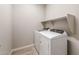 Bright laundry room with side-by-side washer and dryer and a storage shelf above at 17842 W Getty Dr, Goodyear, AZ 85338