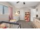 Bedroom features a crib, changing table, and bookcase, accentuated by soft lighting and a neutral palette at 2301 E Alpine E Ave, Mesa, AZ 85204