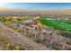 Expansive aerial view of a desert community with golf course, mountain views and tile roofs at sunset at 2430 S Geronimo Head Trl, Gold Canyon, AZ 85118